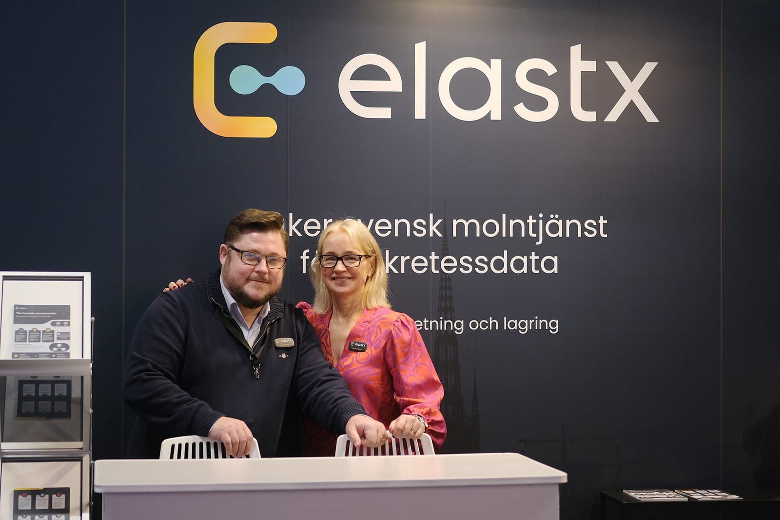 Elastx säljare, Jens och Lovisa, står framför Elastx monter på mässan. 